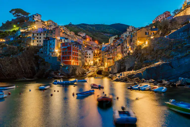 Riomaggiore lit up in the evening with boats