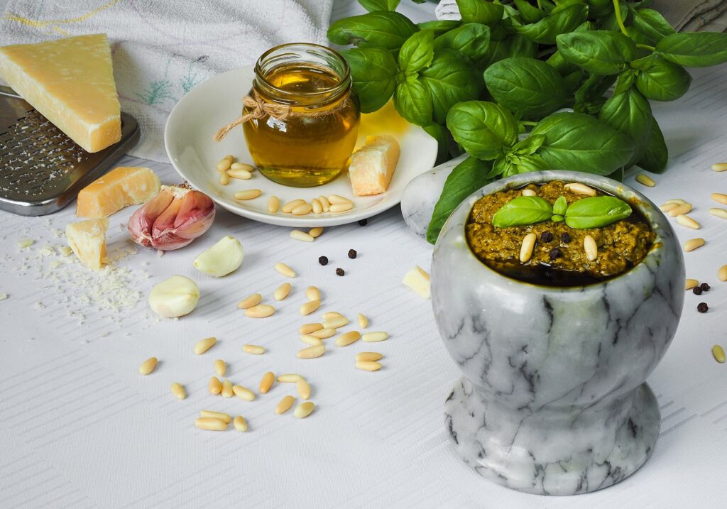Ingredienti del pesto alla genovese: basilico, pinoli, aglio, Parmigiano, olio e un mortaio di marmo con il pesto