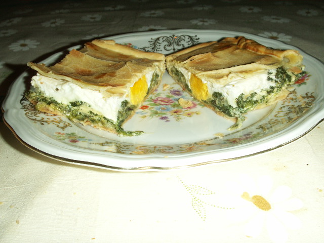 Due fette di torta pasqualina: strati di erbette, prescinsêua e uovo intero sotto la sfoglia